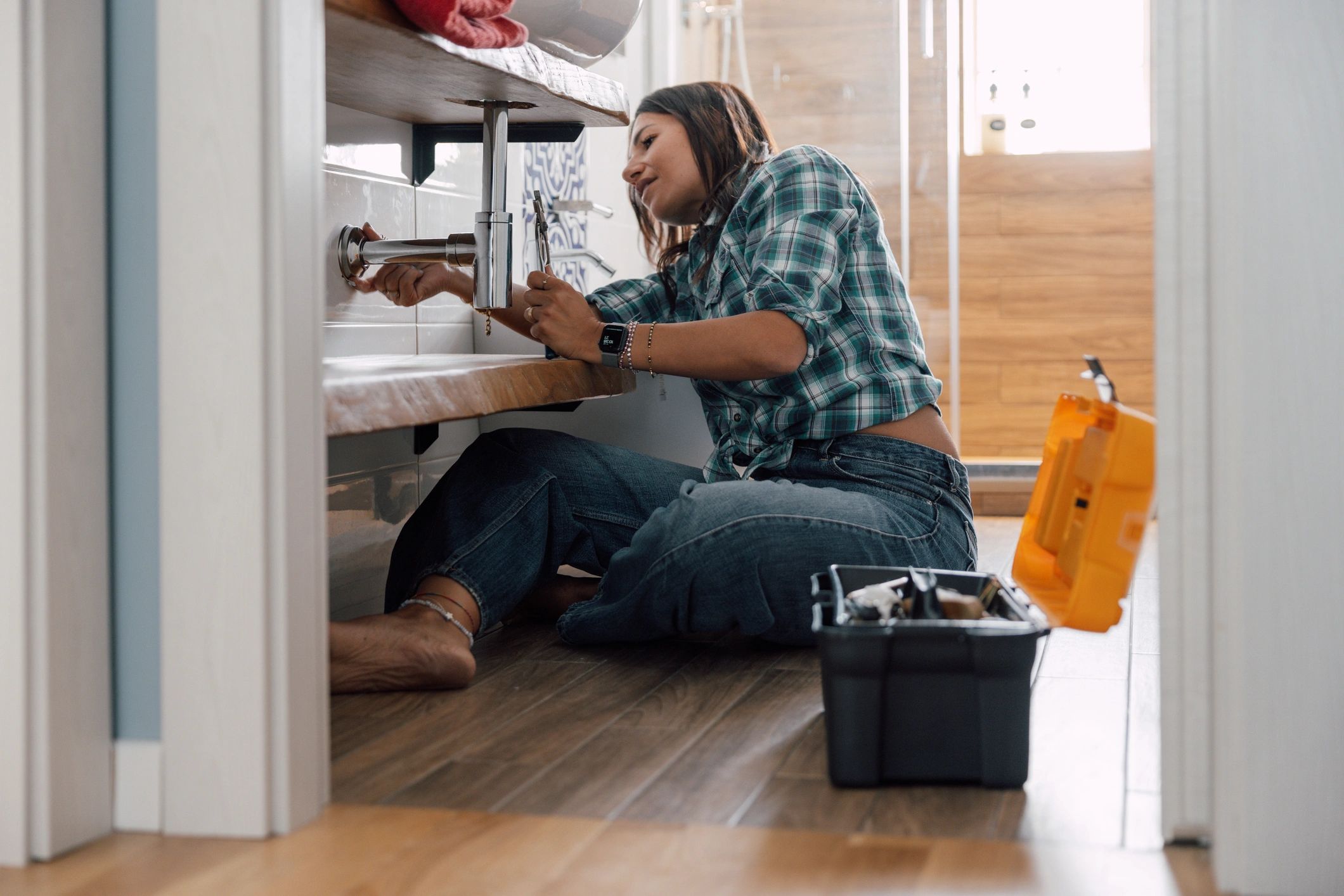 Technician repairing pipes under a sink